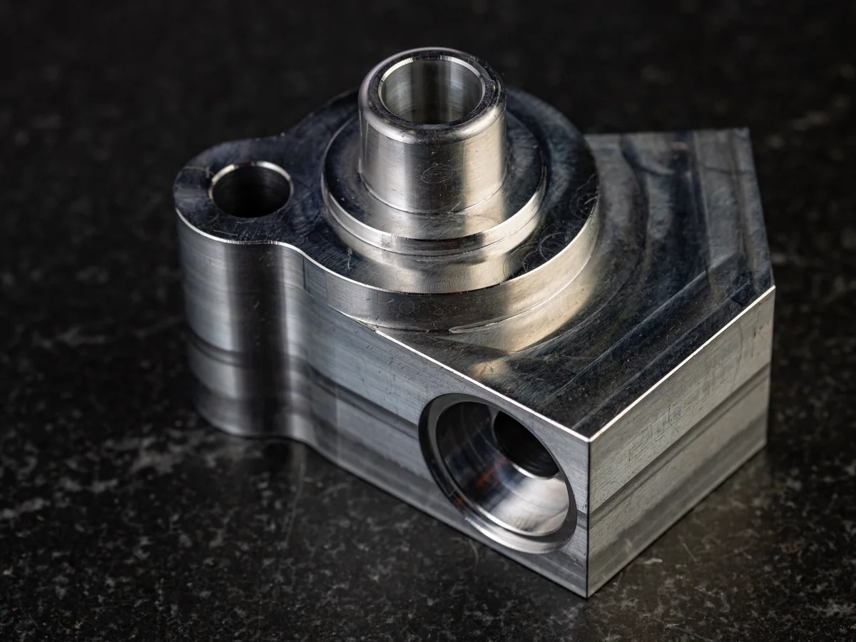 Precision machined aluminum connector block with stepped bore and cylindrical features for automotive application